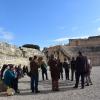 El grupo de participantes en la actividad escuchan las explicaciones en el anfiteatro romano